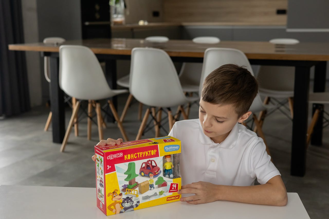 Young boy holding a construction toy set in a stylish indoor setting with modern furniture.
